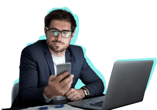hombre en computador mirando telefono